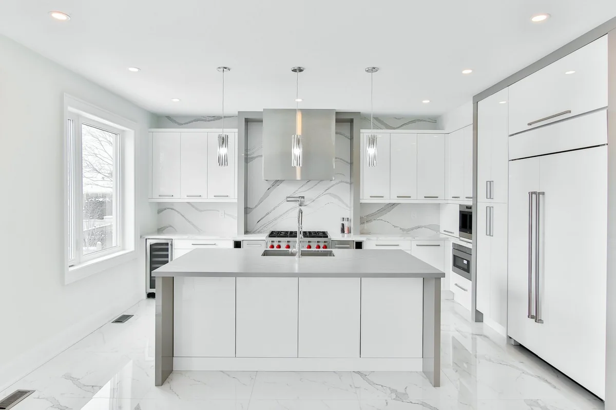 White kitchen with gray-veined marble-look surfaces and an island